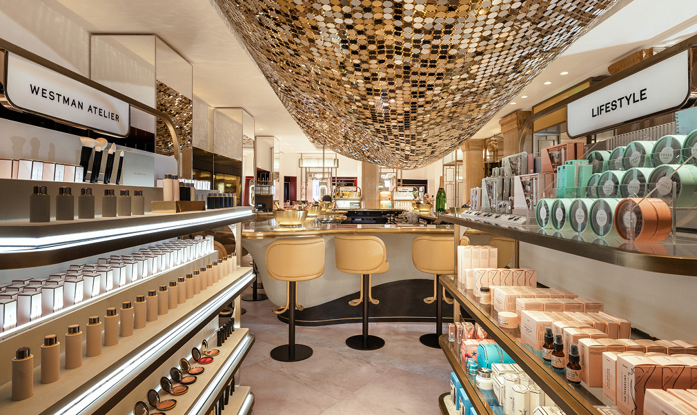 View of the Moët & Chandon Champagne Bar within Harrods Beauty Hall, showcasing luxury beauty displays alongside the golden champagne counter beneath a statement ceiling installation.