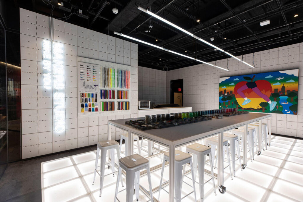 Nike By You customisation studio with illuminated flooring, creative workstations, and vibrant material samples for sneaker personalisation.