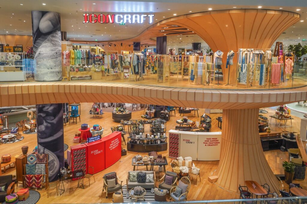 Interior view of ICONCRAFT at ICONSIAM, showcasing contemporary Thai craftsmanship with wooden architectural structures, artisanal furniture, textiles, and lifestyle products displayed across two levels.