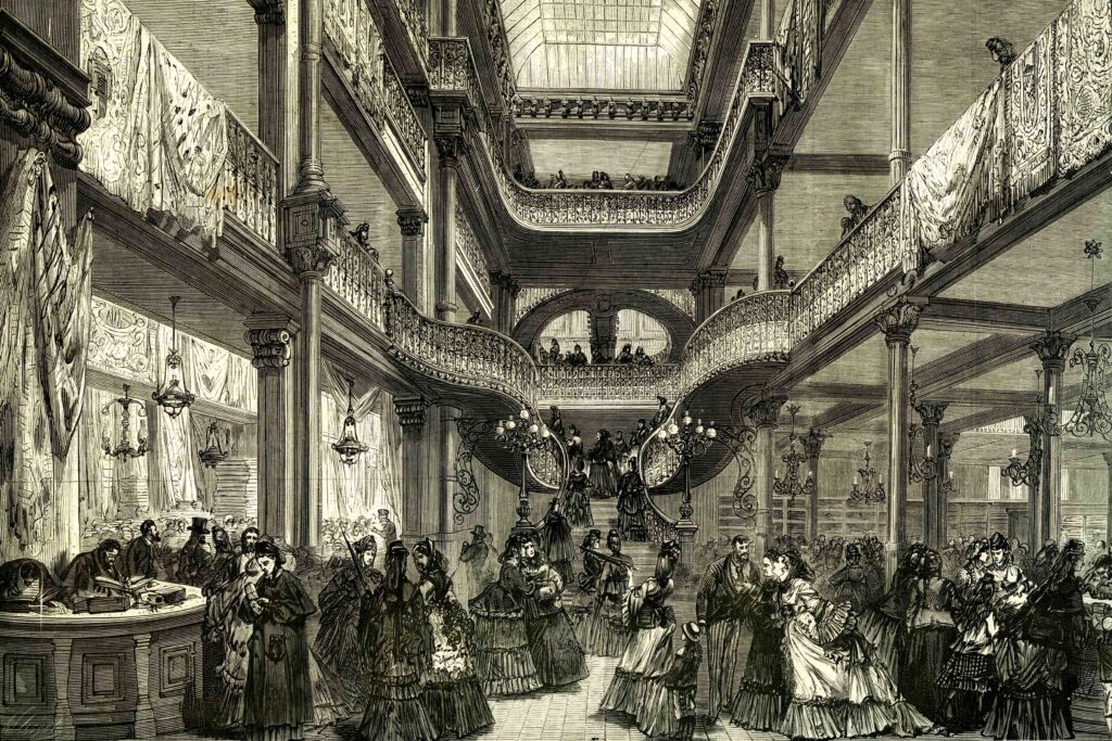 black pen drawing of the interior of Le Bon Marché in Paris from 1872, depicting elegantly dressed shoppers on grand staircases and balconies within an ornate, multi-level department store featuring ironwork railings, tall columns, and a glass skylight.