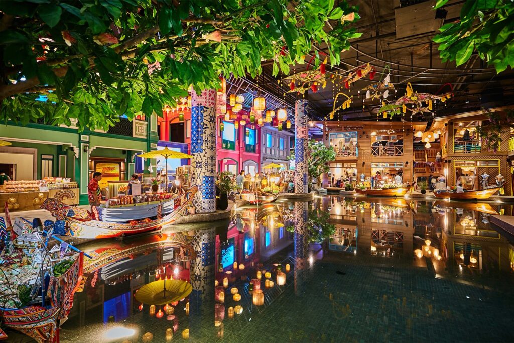 Indoor floating market at SOOKSIAM within ICONSIAM, featuring colorful boats, traditional Thai architecture, vibrant lanterns, and decorative tiles reflected on the water.