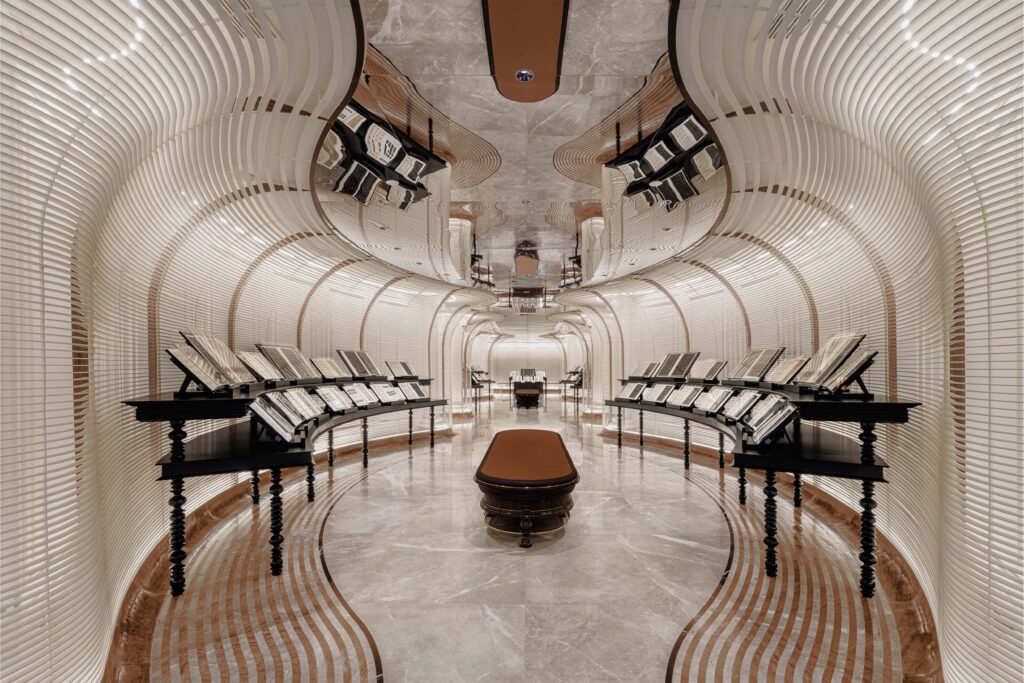 Futuristic restroom interior with curving white ribbed walls, marble flooring, and black display tables showcasing elegant design materials.