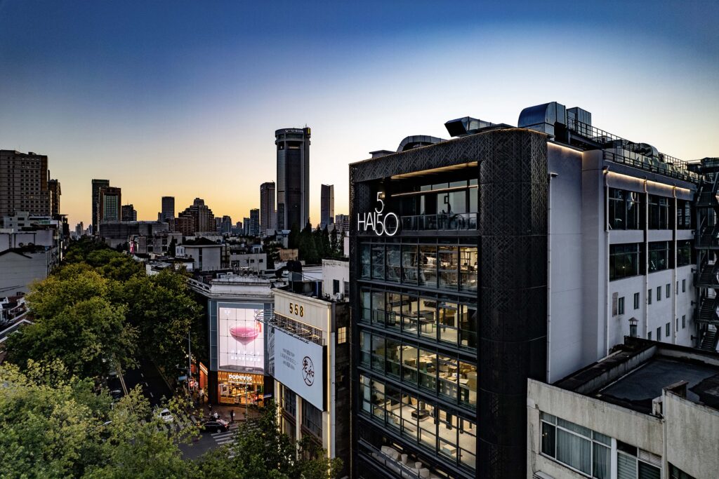 Contemporary glass façade of HAI 550 building in an urban setting at sunset, blending industrial and modern architectural design.