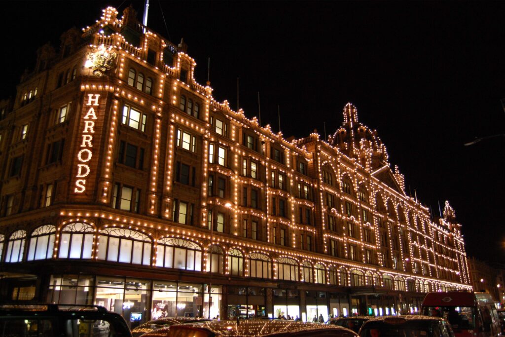 Night view of Harrods department store in London illuminated by thousands of lights, representing timeless retail design principles and enduring luxury heritage.