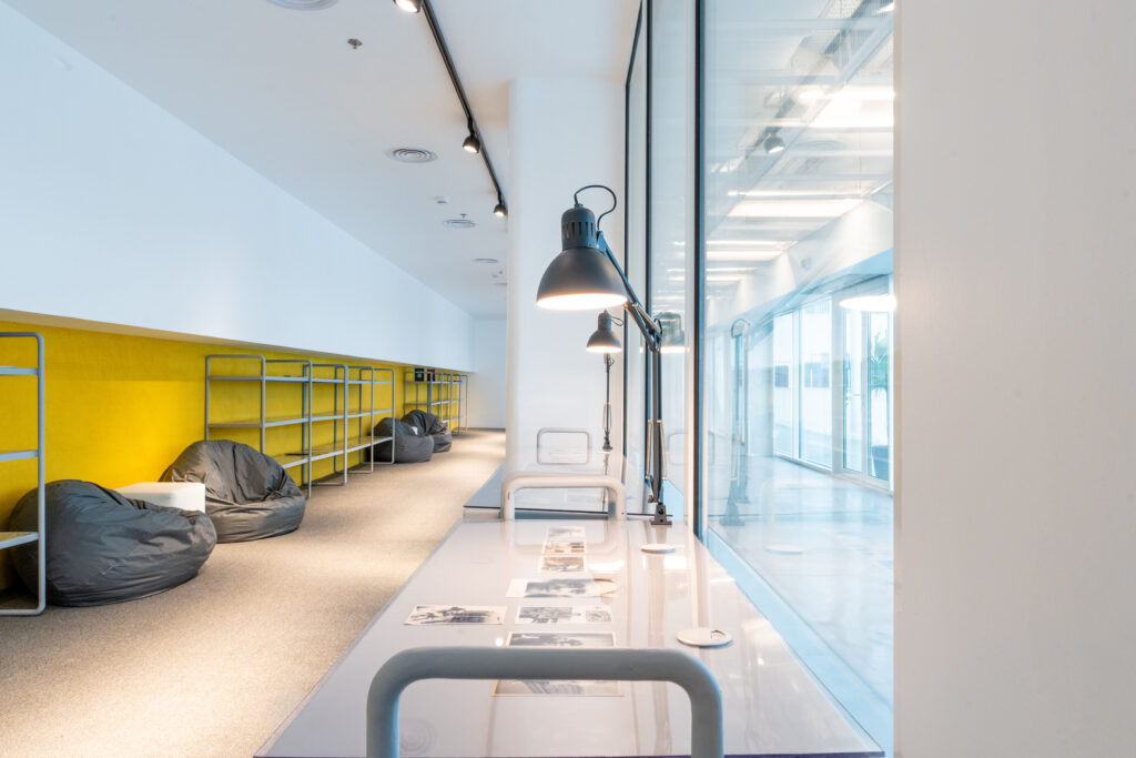 Hayy Archive reading and research area inside Hayy Cinema, with clean minimalist interiors, yellow accents, and natural daylight.