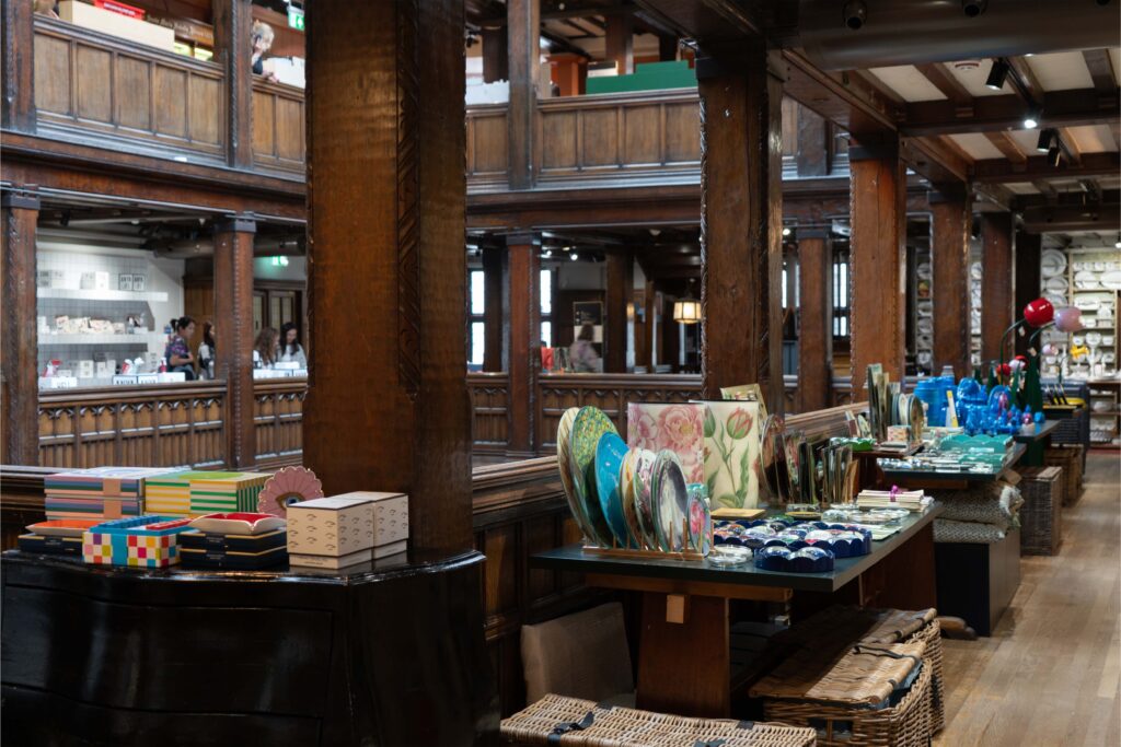 Interior of Liberty London showcasing its signature wooden galleries and displays of colourful homeware, ceramics, and design objects.