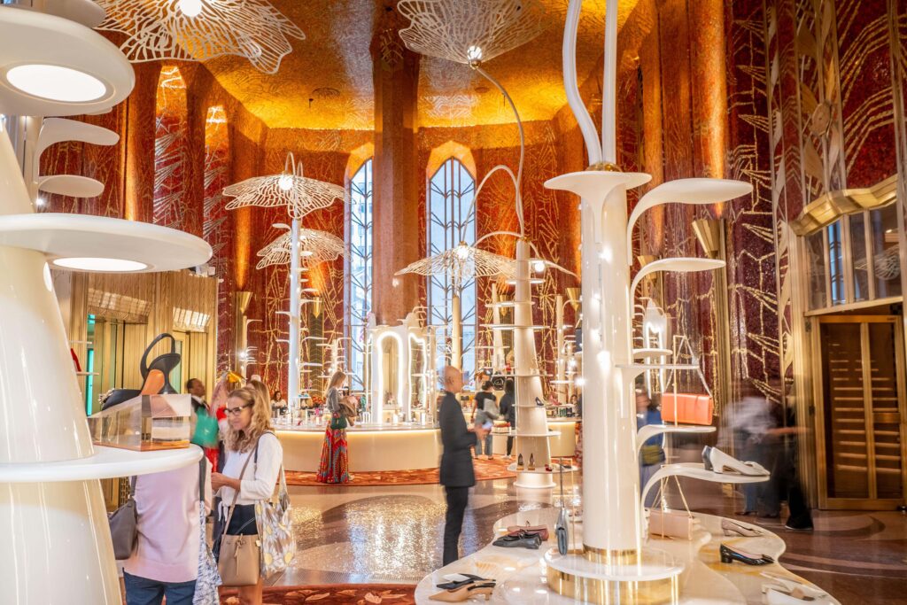 Interior of Printemps’ New York City flagship store featuring a sculptural, art-inspired retail space with organic white display structures, warm golden lighting, and a mosaic-like ceiling design, creating an immersive luxury shopping environment.