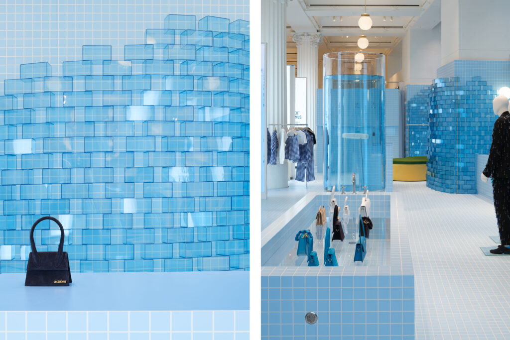 Close-up of the Jacquemus “Le Bleu” installation at Selfridges, featuring translucent blue glass tiles arranged in a wave pattern and a display counter showcasing the brand’s signature handbags.