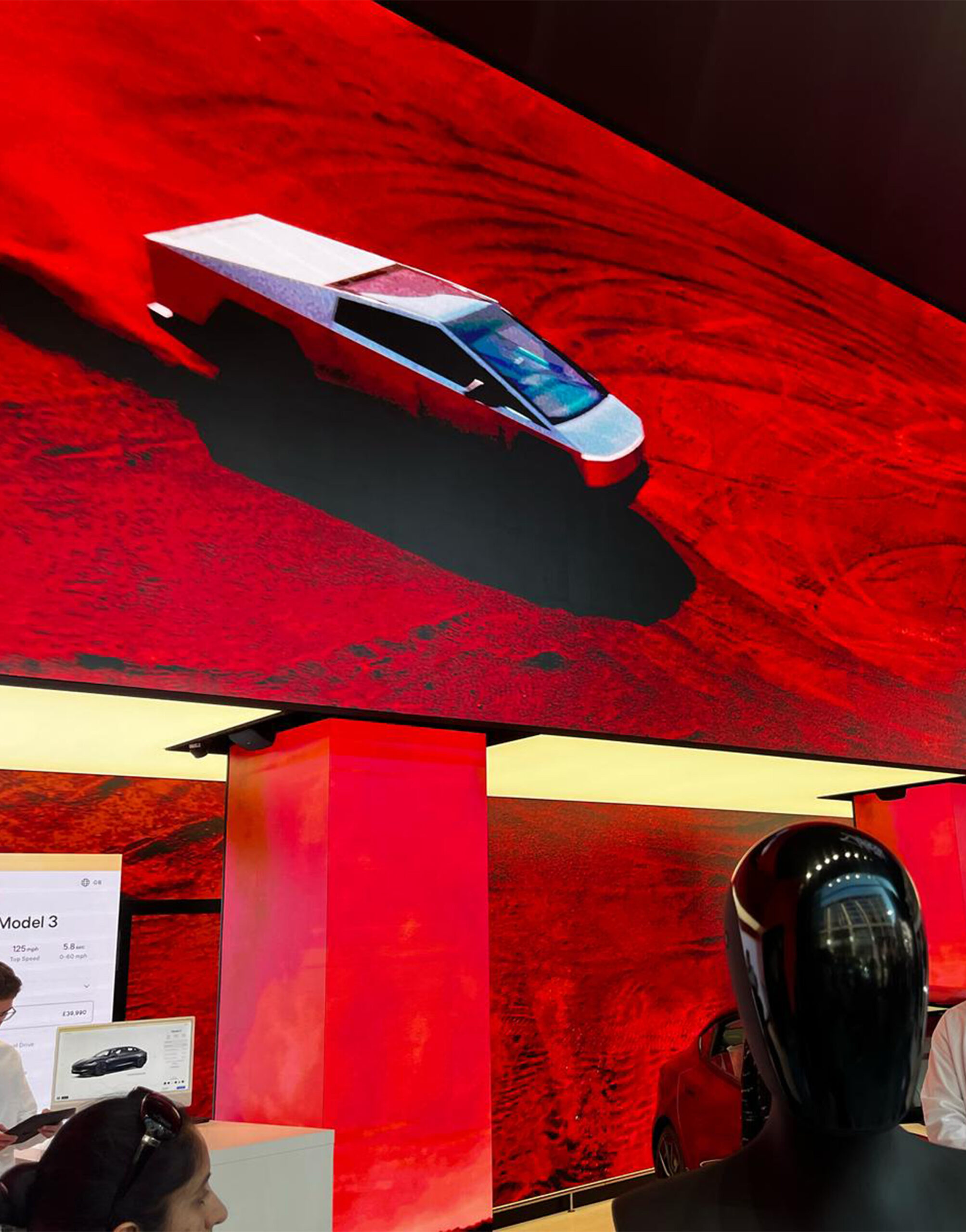 Immersive Tesla showroom featuring a dynamic digital display of the Cybertruck on a red desert landscape, blending physical vehicles with virtual storytelling.